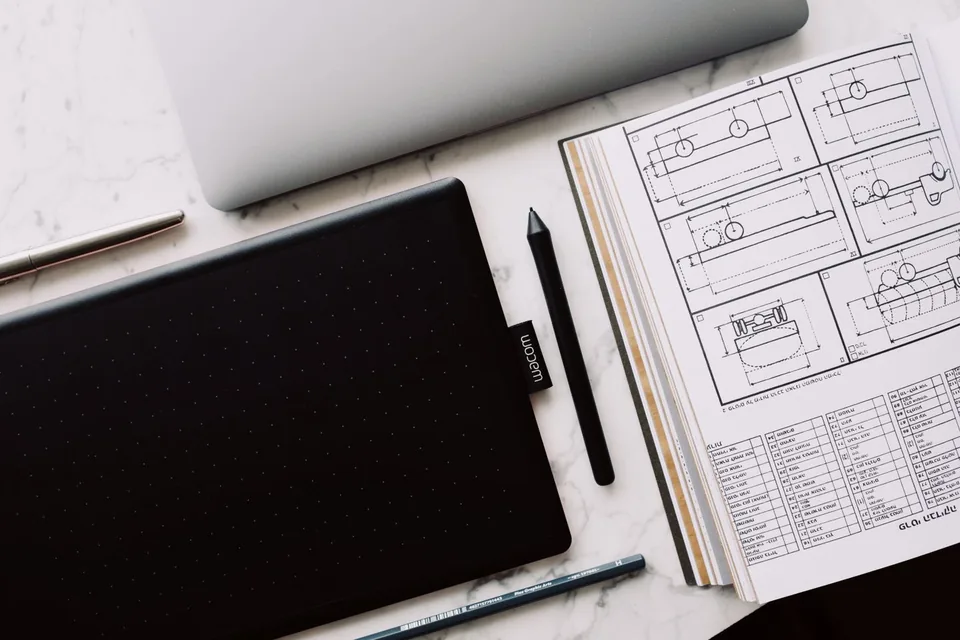 Drawing tablet beside a sketchbook of technical diagrams