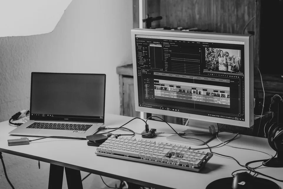 Laptop and desktop monitor showing a video editing timeline